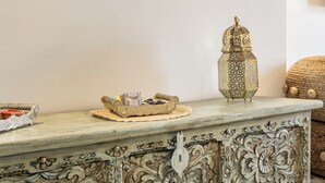 Une pièce comprenant une console décorative, une œuvre d’art encadrée représentant un bâtiment et un sol à motifs.