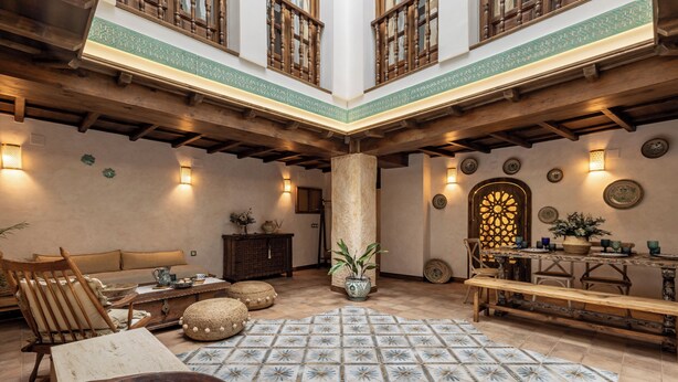 Un intérieur spacieux avec un plafond haut, des poutres en bois, une colonne centrale et un sol à motifs.