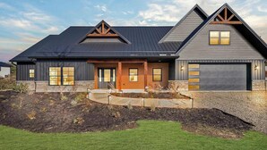 A modern two-story house with a dark roof, a garage, and a landscaped front yard. - Juniper Presents: NEW Luxe Stay w Hot Tub, Fire Pavilion Nr Lake MI (Berrien County)