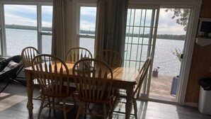 A dining area with a table and chairs, large windows with a view of a body of water, and a sliding glass door leading outside. - Gorgeous 4 bedroom home , sitting on beautiful Davidson lake .. (Dumfries)