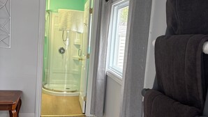 A room with a wooden floor, a bench, a glass shower enclosure, a window with curtains, and a chair. - Gorgeous 4 bedroom home , sitting on beautiful Davidson lake .. (Dumfries)