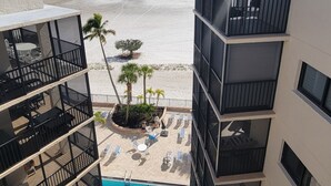 Una piscina con vistas a la playa, un edificio con balcones y un cielo despejado.