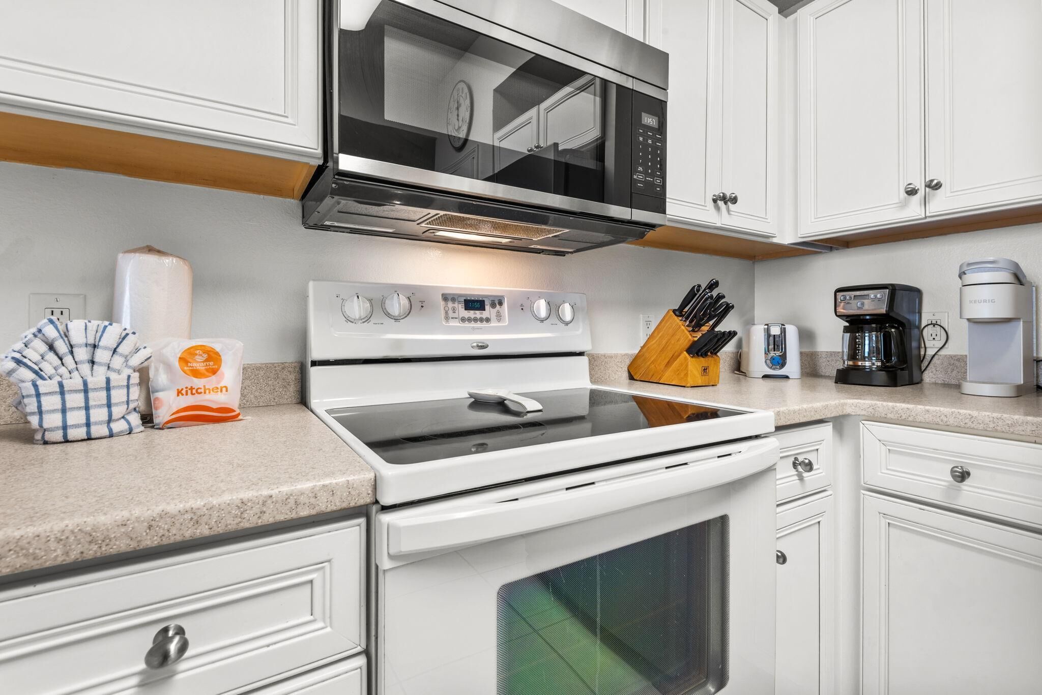 A kitchen with a microwave, stove, coffee maker, and a knife block.