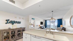 A modern kitchen with a large island, a dishwasher, and a view to the living area. - Summerwind West 1403 - The Beach Fort (Navarre)