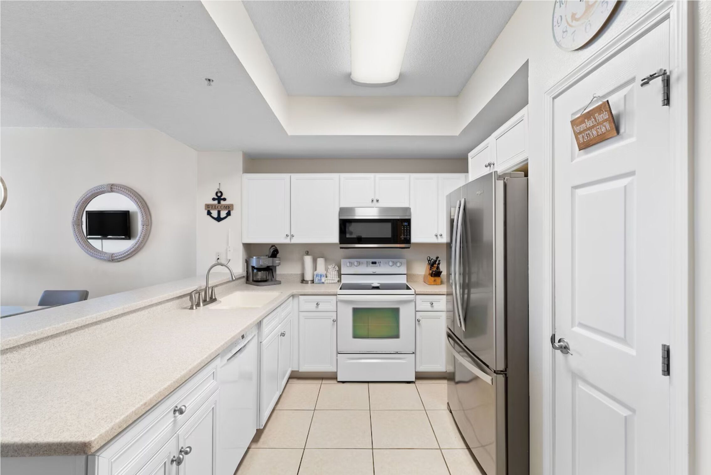 A modern kitchen with white cabinets, a stainless steel refrigerator, a microwave, and an oven.
