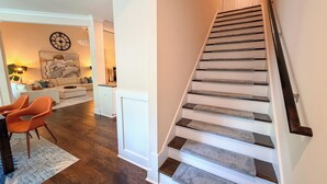 A staircase with wooden steps and a handrail, leading to a landing with a white door.