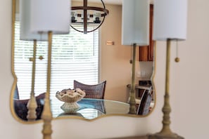 A room with a dining table, chairs, a chandelier, and a window with blinds.