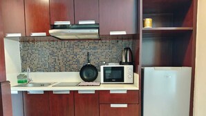 A compact kitchen with a microwave, stove, and a refrigerator.