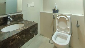 A bathroom with a marble sink, a toilet, and a mirror.