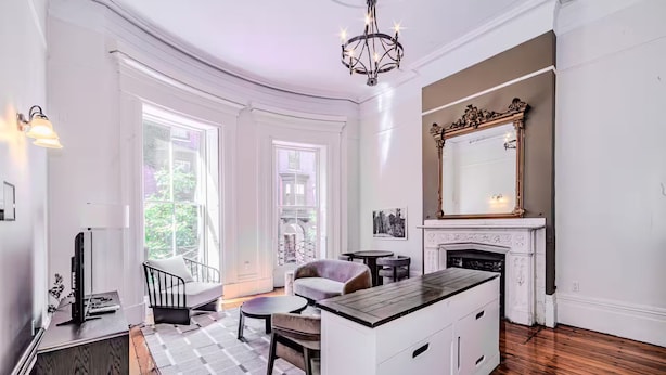 A spacious living room with a fireplace, large windows, and a chandelier. - Beacon Hill - Historic Elegance (Boston)