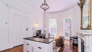 A room with a white door, a chandelier, a fireplace, and a large window. - Beacon Hill - Historic Elegance (Boston)