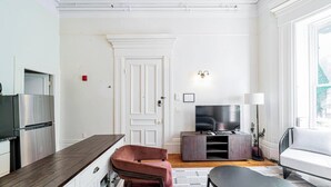 A modern living room with a kitchen area, a flat-screen TV, a sofa, and a dining table. - Beacon Hill - Historic Elegance (Boston)