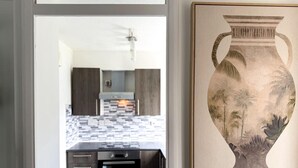 Une cuisine moderne avec des meubles de rangement aux couleurs sombres, un four encastré et un revêtement mural en carreaux.