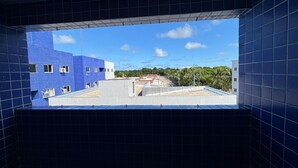 En vy genom ett fönster med blå kakelbeklädda väggar, en klar himmel och en byggnad med en blå fasad.