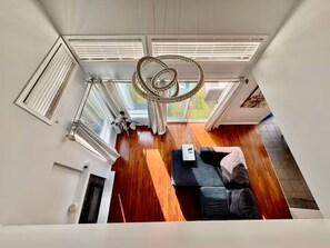 A modern interior with a wooden floor, a sofa, a table, and a unique circular light fixture.
