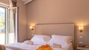 Ett hotellrum med en säng, sänglampor, ett litet bord och utsikt genom ett fönster.