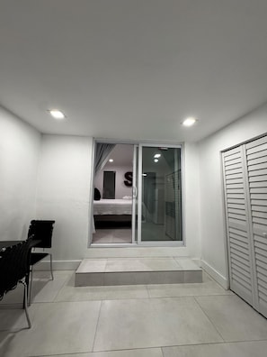 Ein Zimmer mit Bett, Schreibtisch und einer Schiebetür zum Badezimmer.