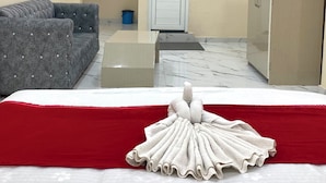 Une chambre d’hôtel avec un lit, un canapé gris, une armoire, une porte et une petite table.