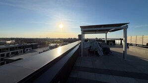 Eine Dachterrasse mit Blick auf die Stadtlandschaft, ein überdachter Sitzbereich und ein Pool.