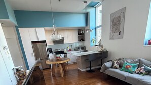 Eine moderne Küche mit einer zentralen Kochinsel, einem Essbereich mit Holztisch und einem Wohnzimmer mit einer Couch.
