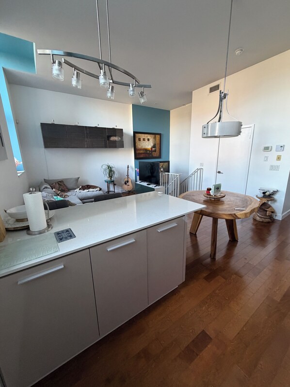 Une cuisine moderne avec un plan de travail blanc, des meubles gris et une table à manger en bois.