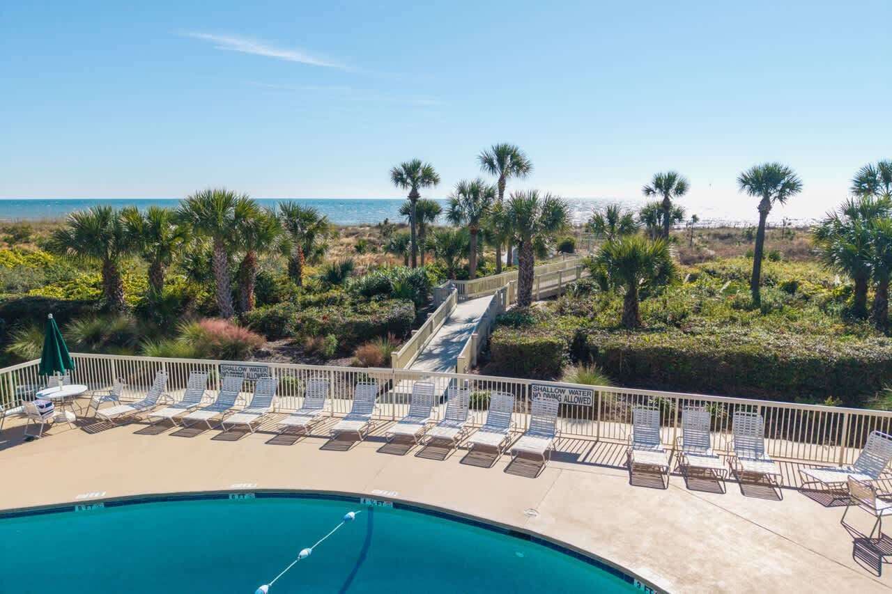 A poolside area with lounge chairs and a sign indicating shallow water.