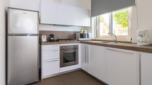 Eine moderne Küche mit weißen Schränken, Edelstahlgeräten, einer Mikrowelle, einem Toaster und einer Kaffeemaschine.