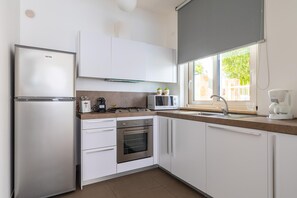 A modern kitchen with white cabinets, stainless steel appliances, a microwave, a toaster, and a coffee maker.