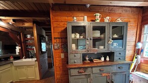Una cocina rústica con armarios de madera, un lavabo y una zona de comedor con una mesa y sillas de madera.