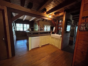 Ein Holzblockbau-Innenraum mit Küchenbereich, Holzböden und einem sichtbaren Essbereich.