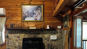 Un interior rústico con chimenea de piedra, vigas de madera, un cuadro enmarcado sobre la chimenea y un letrero que dice 'Happy Place'.