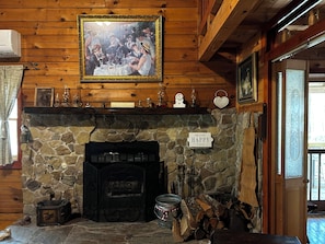 Ein rustikales Interieur mit Kamin aus Stein, Holzbalken, einem gerahmten Bild über dem Kamin und einem Schild mit der Aufschrift 'Happy Place'.