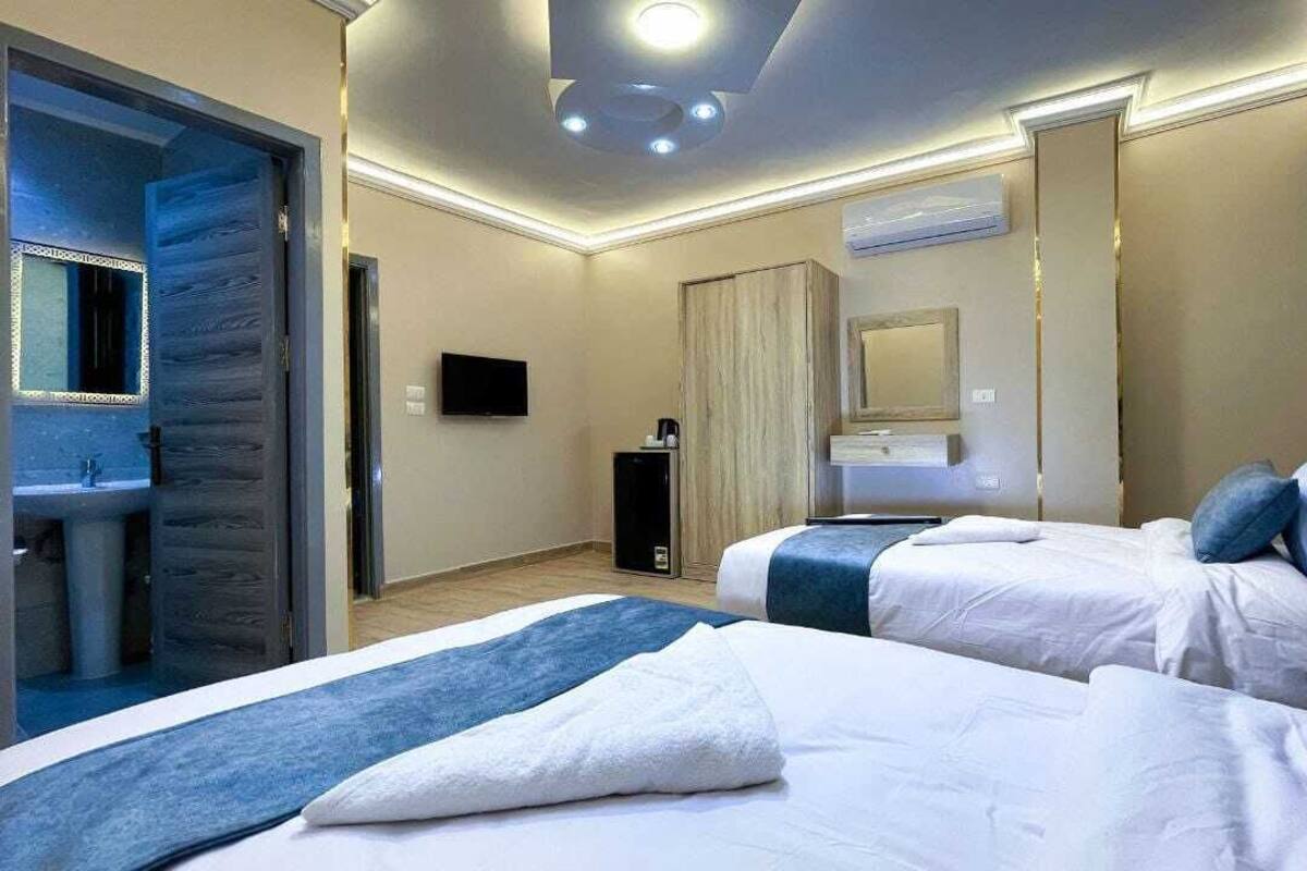Habitación de hotel con dos camas, baño, televisor y espejo.