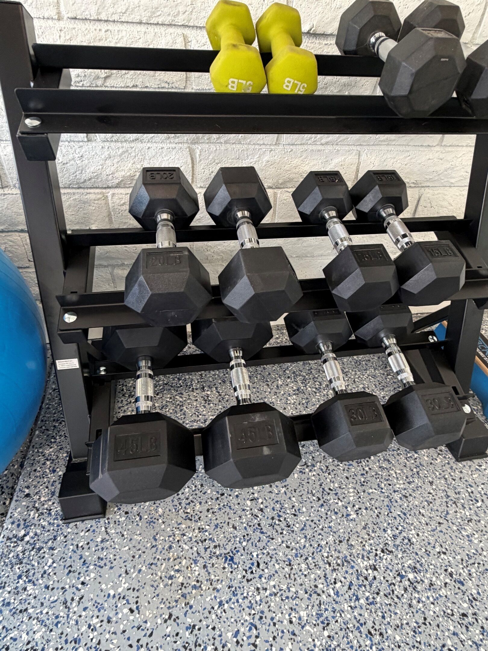 A weightlifting rack with various dumbbells, including some labeled with weight.