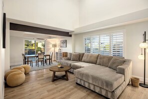 A living room with a sectional sofa, round coffee table, and ottomans. - Mountain View Retreat (Scottsdale)