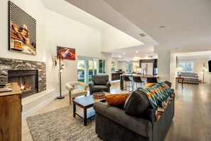 A spacious living room with a fireplace, a dining area, and a kitchen in the background. - Mountain View Retreat (Scottsdale)