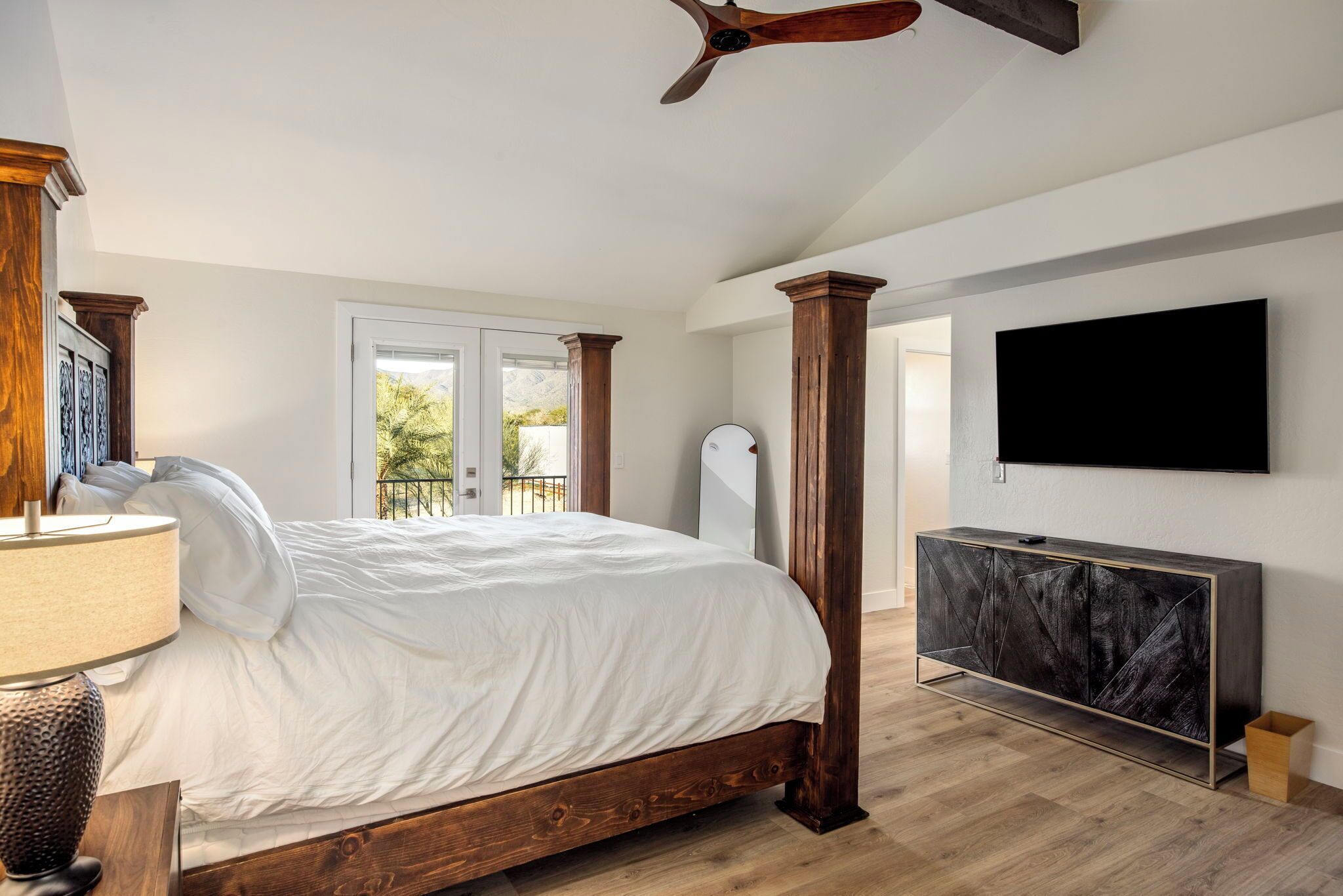 Una camera da letto con un letto, una TV, un armadietto in legno e una ventola a soffitto.