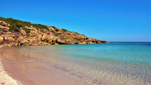 A beach with clear water, rocky cliffs, and greenery. - Marzamemi on the beach SicilyMyHome (Marzamemi)