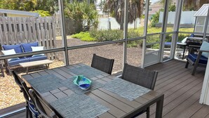 An outdoor patio with a table, chairs, and a view of the backyard. - Steps to Beach - Prime Location Beach Bungalow – Beach Gear (Holmes Beach)