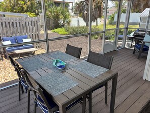 An outdoor patio with a table, chairs, and a view of the backyard.