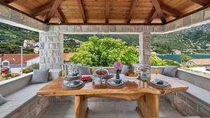 Un tavolo di legno apparecchiato per la colazione, con pilastri in pietra, vista su un paesaggio verde e un muro in pietra.