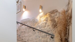 Una scala con pareti in pietra, una ringhiera e un vaso con piante essiccate.