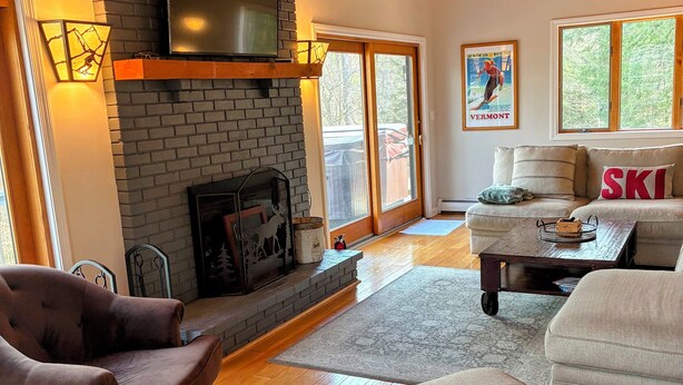 Una sala de estar con chimenea, un sofá, una mesa de centro y un televisor.