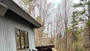 Una terraza de madera con barandilla, un banco y una ventana.