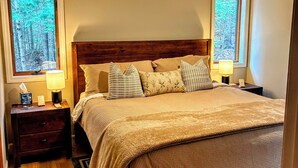 Un dormitorio con cabecera de madera, una cama con varias almohadas, dos mesitas de noche con lámparas y un ventilador de techo.