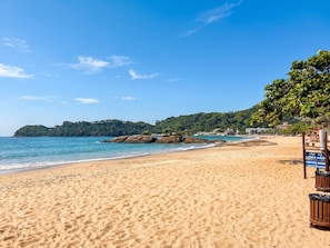 Uma praia com águas azul-claras, areal arenoso e uma placa.