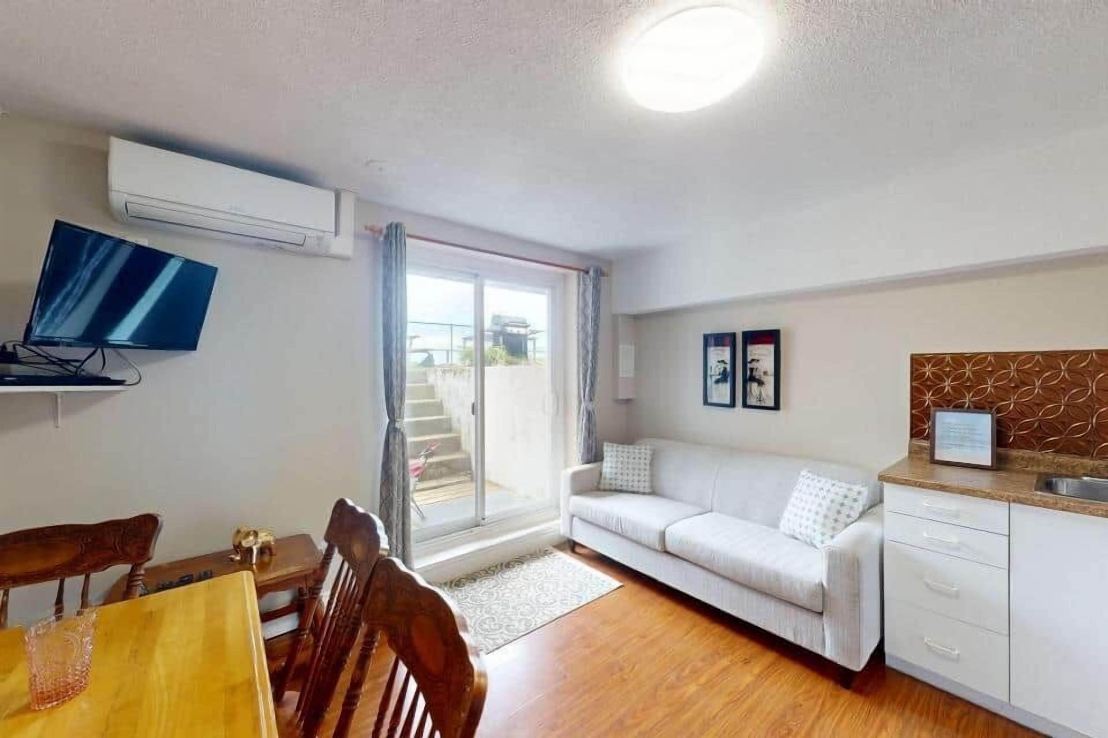 A compact living space with a dining area, a sofa, a kitchenette, and a TV.