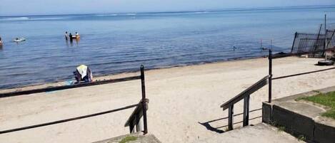 A beach with a concrete walkway and a metal fence.
