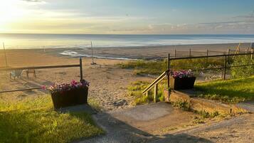 A coastal pathway with a metal fence, a grassy area, and a view of the sea.
