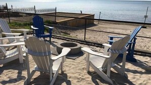 Een zitgedeelte aan het strand met Adirondack-stoelen en een vuurkuil.